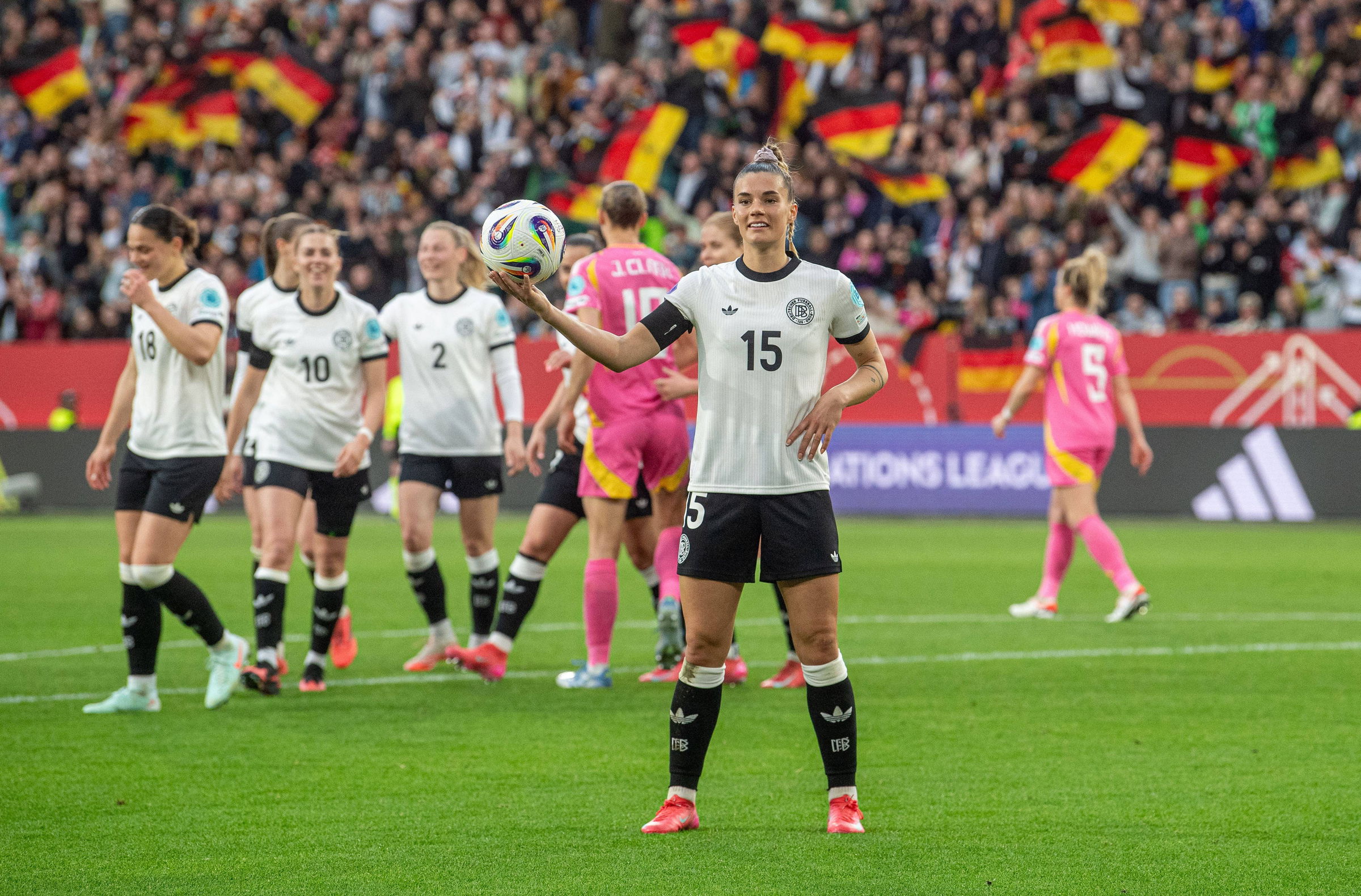 Mitglieder der deutschen Frauen-Nationalmannschaft beim Jubeln auf dem Feld vor einer Zuschauermasse die auf der Tribüne Deutschland-Fahnen schwenkt