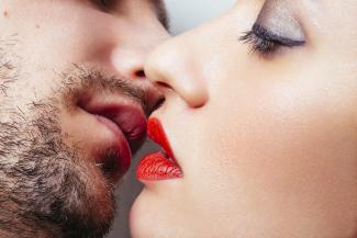 Mann mit Bart küsst Frau mit roten Lippen