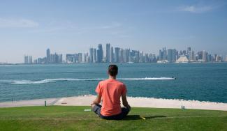 Ein Mann meditiert vor einer Skyline.