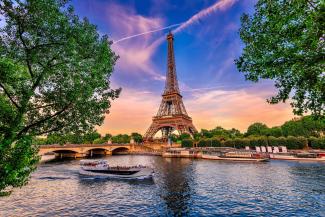 Eiffelturm bei farbenfrohem Sonnenuntergang mit Seine und Bäumen im Vordergrund