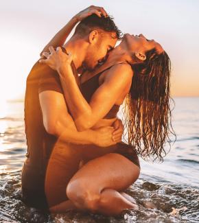 Junges Paar eng umschlungen hüfthoch im Meer bei Sonnenuntergang